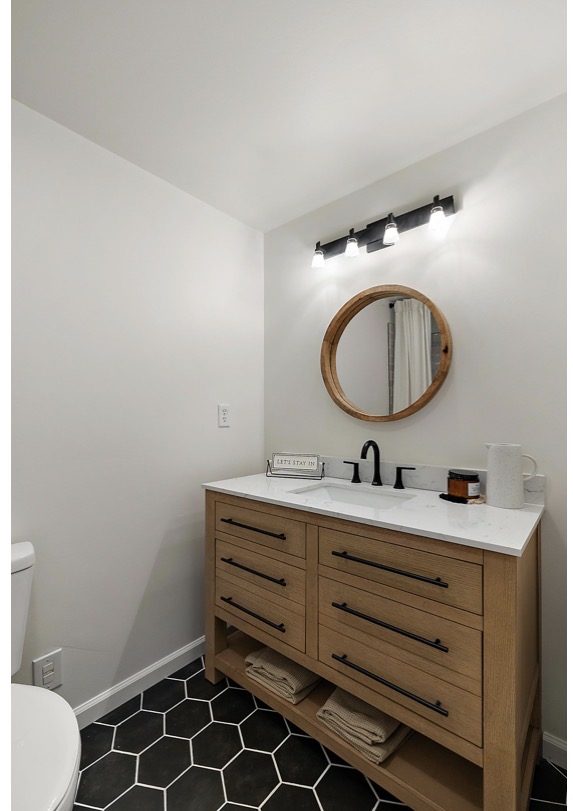 Custom bathroom vanity with white quartz countertop, black faucet, and black hexagon floor tile — Downriver Michigan